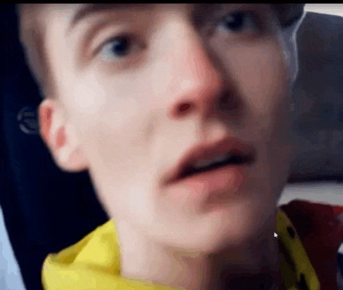 a close up of a young man 's face with a yellow hoodie on .