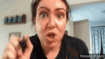 a woman is making a funny face and pointing at the camera