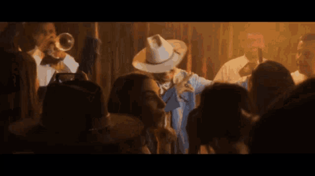 a man in a cowboy hat stands in front of a crowd