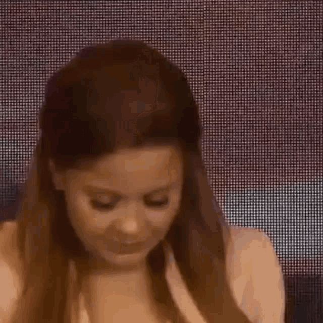 a woman with long hair is standing in front of a screen and looking at the camera .