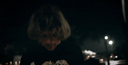 a man with long hair is holding a donut in his hand