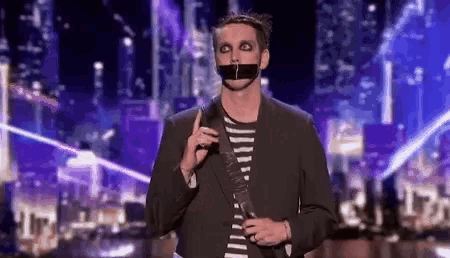 a man with a tape over his mouth is holding a guitar .