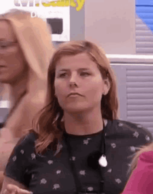 a woman is making a funny face while standing next to another woman in a room .