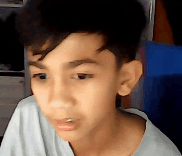 a close up of a young boy 's face with a white shirt on