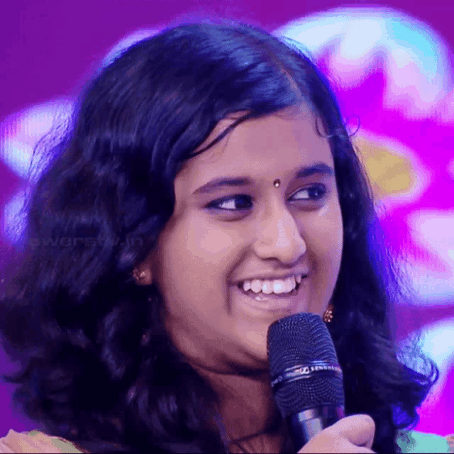 a young girl is smiling while holding a microphone