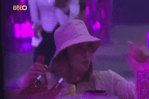 a woman in a bucket hat is holding a bottle in front of a sign that says bbgo