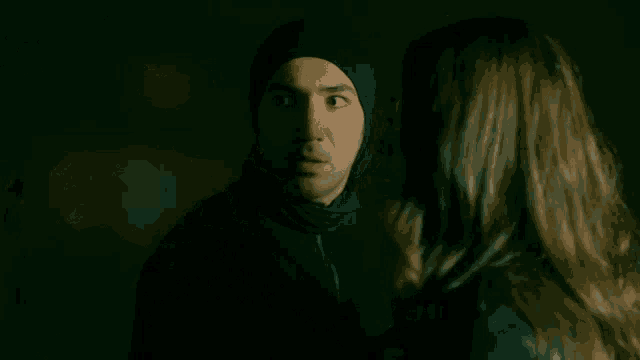 a man and woman are looking at each other in the dark