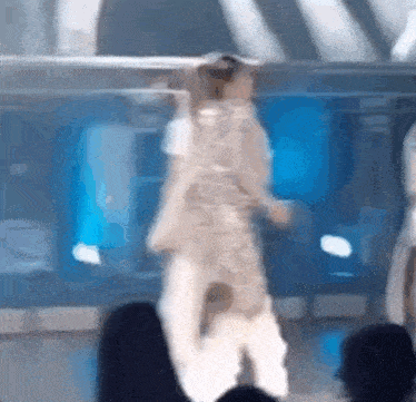 a woman is dancing on a stage in front of a crowd .