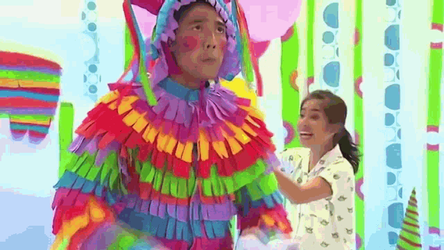 a man in a colorful costume is standing next to a girl in a room .