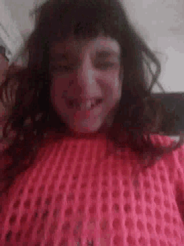 a woman in a pink sweater is laying on her back with her mouth open .