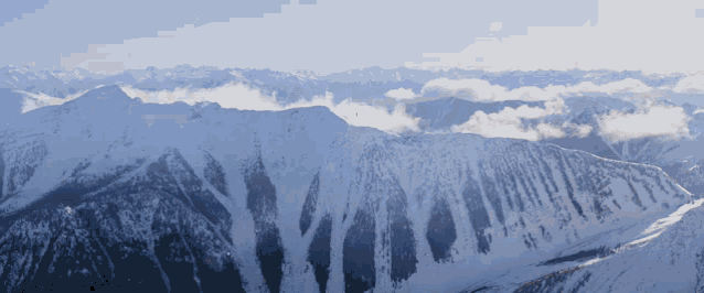 a snowy mountain range with trees on the side