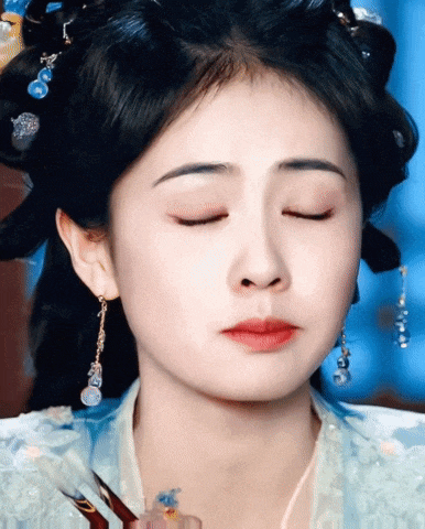 a close up of a woman 's face with her eyes closed and earrings
