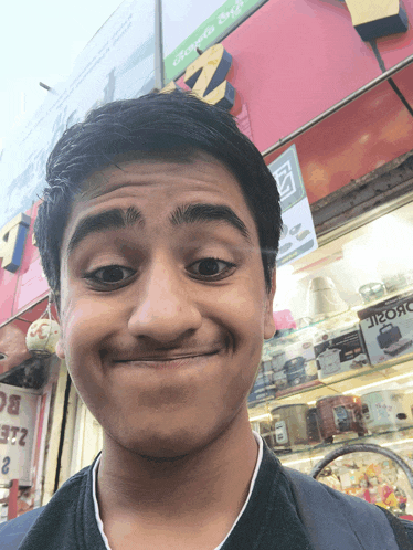 a young man making a funny face in front of a store with a sign that says ' ironc ' on it