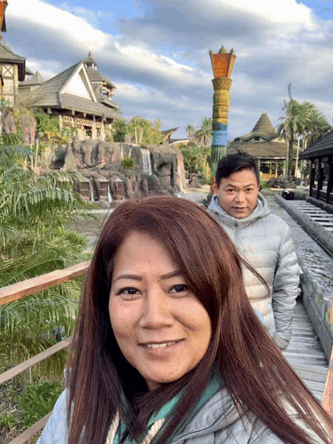 a man and a woman are standing on a wooden bridge