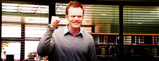 a man in a grey sweater is giving a fist pump