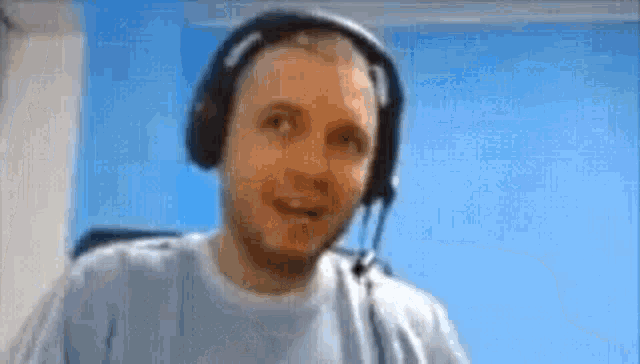 a man wearing headphones and a microphone is looking at the camera and smiling .