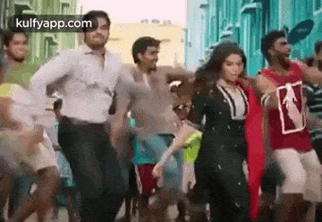 a group of people are dancing in a street in front of a building .