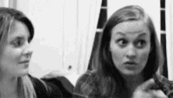 two women are standing next to each other and making funny faces .