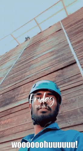 a man wearing a helmet stands in front of a wooden wall on friday