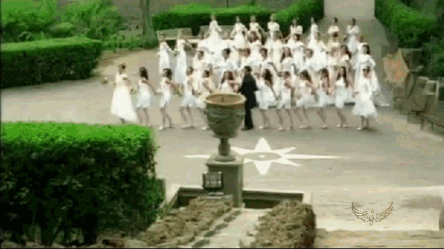 a group of women in white dresses are dancing in front of a fountain