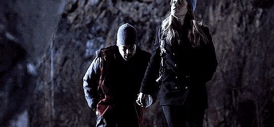 a man and a woman are holding hands while walking in the dark .