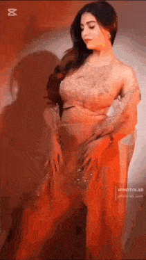 a woman in a red dress is standing in front of a red wall .