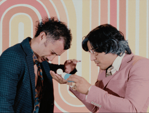 a man in a pink suit holds a bottle of pills
