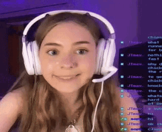 a woman wearing headphones and a microphone is smiling while playing a video game .