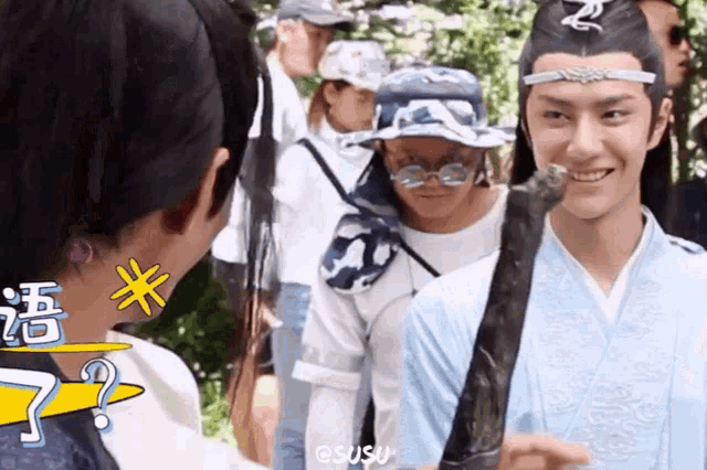 a man in a blue kimono is smiling while holding a sword