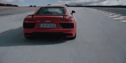 a red audi r8 quattro is driving down a race track .