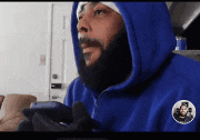 a man with a beard is wearing a blue hoodie and holding a cell phone