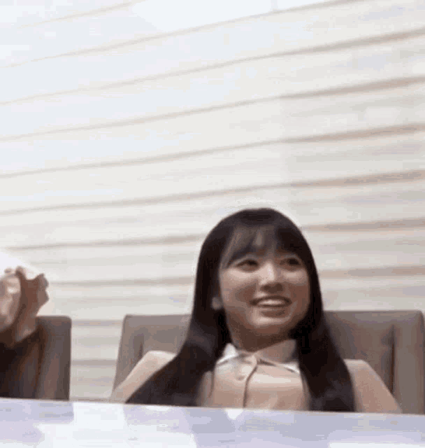a woman is sitting at a table smiling .
