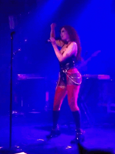 a woman singing into a microphone on a stage in front of a blue light