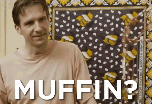 a man in a pink shirt is standing in front of a wall that says muffin on it