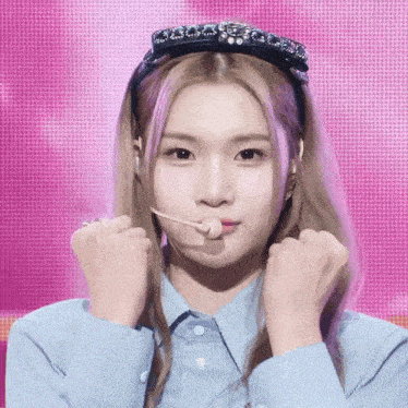a girl wearing a headband and a blue shirt holds her fist up
