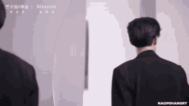 a man in a suit is standing in front of a mirror looking at himself .