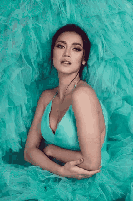 a woman in a turquoise dress is laying on a green background