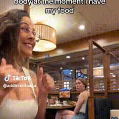 a woman is sitting at a table in a restaurant with a caption that says body at the moment i have my food .