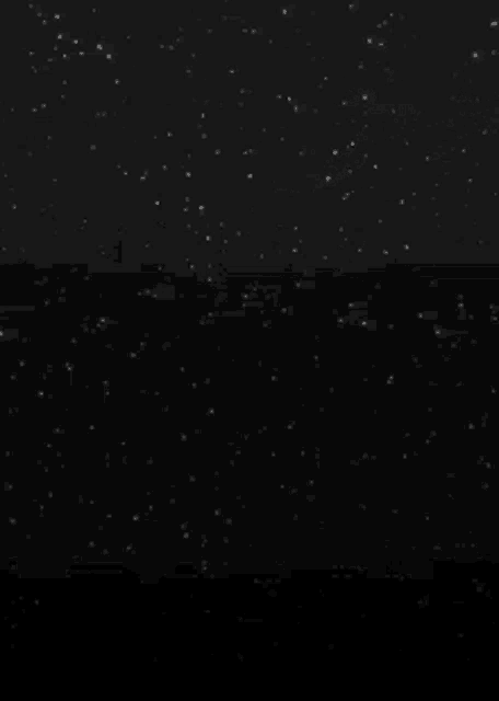 a shooting star is flying through a dark night sky .