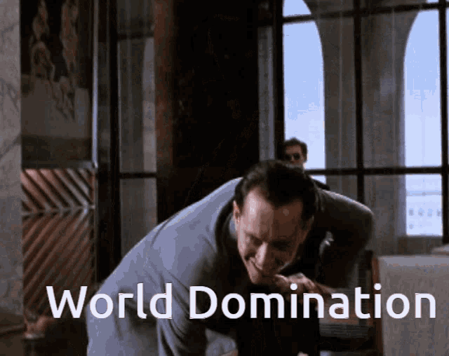 a man in a suit is smiling in front of a sign that says " world domination "
