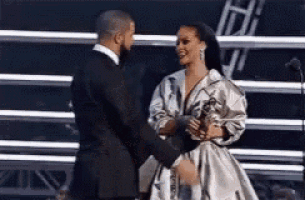 a man and a woman are standing next to each other on a stage holding hands .