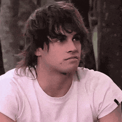 a young man with long hair wearing a white shirt