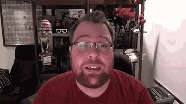 a man with a beard and glasses is sitting in front of a computer screen .