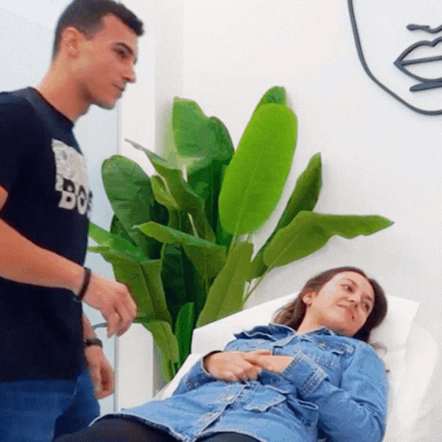 a man standing next to a woman laying in a hospital bed wearing a shirt that says " bo "
