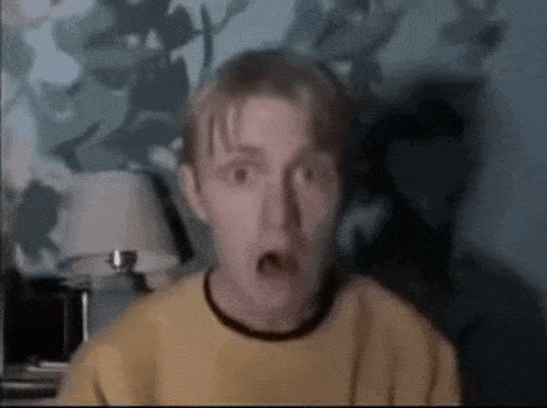 a man with a surprised look on his face wearing a yellow shirt