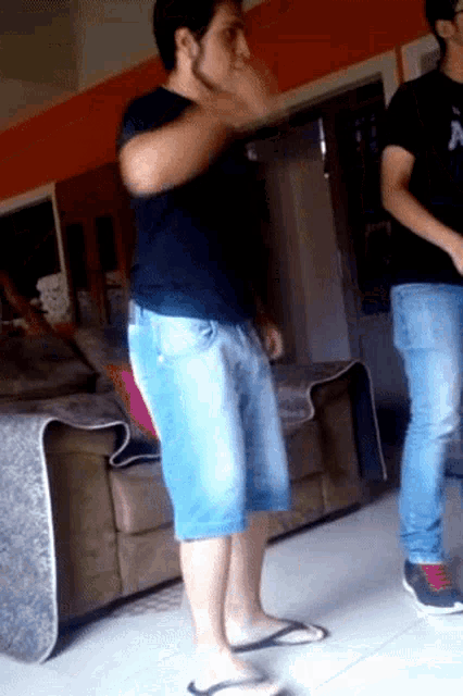 a man in shorts and flip flops is standing in a living room