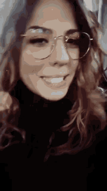 a close up of a woman wearing glasses and smiling