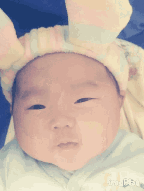 a baby is wearing a headband with bunny ears and the word imgplay is below it