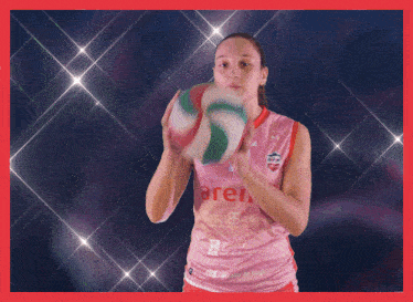 a woman in a pink aren jersey holds a volleyball in her hands