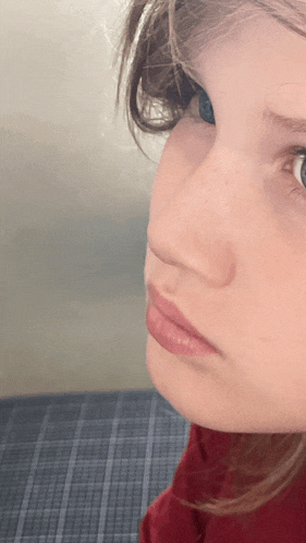 a close up of a young girl 's face with a red shirt on